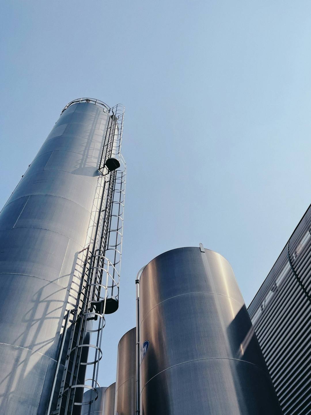 Silos metálicos altos con escaleras contra el cielo despejado